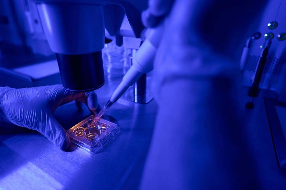 Laboratory worker adding special fluid to plate with embryo samples